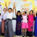 仰光国际学校（YIS）的学生在世界地图前兴奋的举起双手
