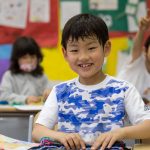 福冈国际学校的小男孩开心的坐在教室