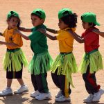 班加罗尔国际学校的小朋友们穿着热带草裙，肩搭肩排成一排