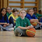 斯德哥尔摩英国国际学校的小男孩抱着篮球坐在地上