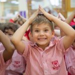 迪拜英语学校的小朋友将双手举在头顶做游戏