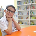 研究科学学校的微笑小男孩在图书馆