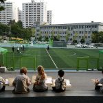 亚太国际学校的学生坐成一排，面对运动场