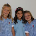 瑞士KSI国际学校的三个小学生穿着校服，开心地看着镜头