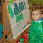 瑞士KSI国际学校的幼儿园男生穿着罩衫，在画画