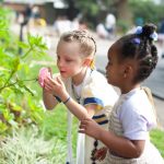 亚的斯亚贝巴国际社区学校的2个小女孩仔细观察和闻花朵
